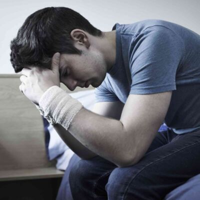 Depressed Young Man With Bandaged Wrists After Suicide Attempt